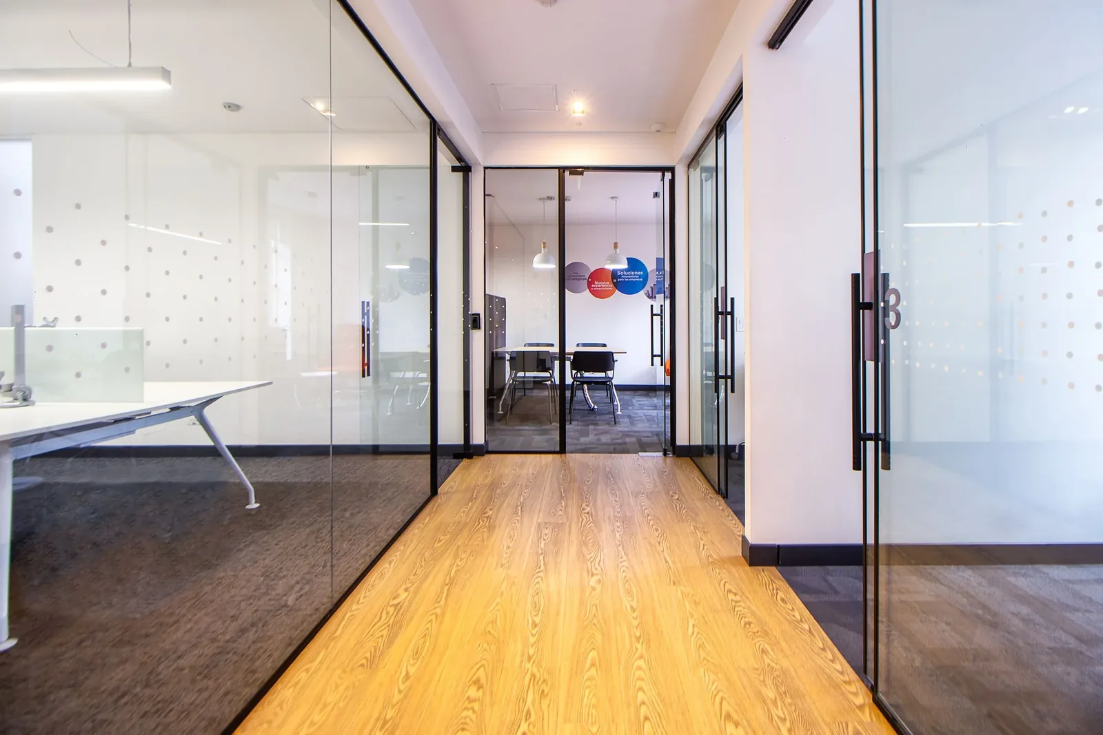 Pasillo corporativo limpio y ordenado entre oficinas de cristal